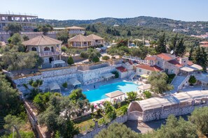 Un resort con piscina, varias edificaciones y un paisaje montañoso de fondo.