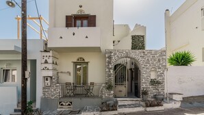 A white building with a stone facade, a balcony, and a door. - Studio Apartment 'En Tino 1' with Balcony, Wi-Fi and Air Conditioning (Tinos)