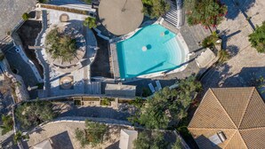 Vista aerea di un resort con piscina, un'area salotto circolare e un portico coperto.