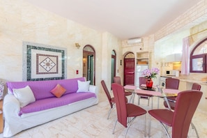 Un intérieur moderne avec un canapé violet, des chaises rouges, une table à manger et un coin cuisine.