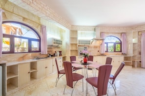 Une cuisine moderne avec des comptoirs en marbre, un coin repas avec des chaises rouges et de grandes fenêtres avec des rideaux.