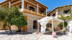 Un bâtiment doté d’un toit en tuiles, d’un balcon et d’un espace extérieur aménagé avec des parasols.