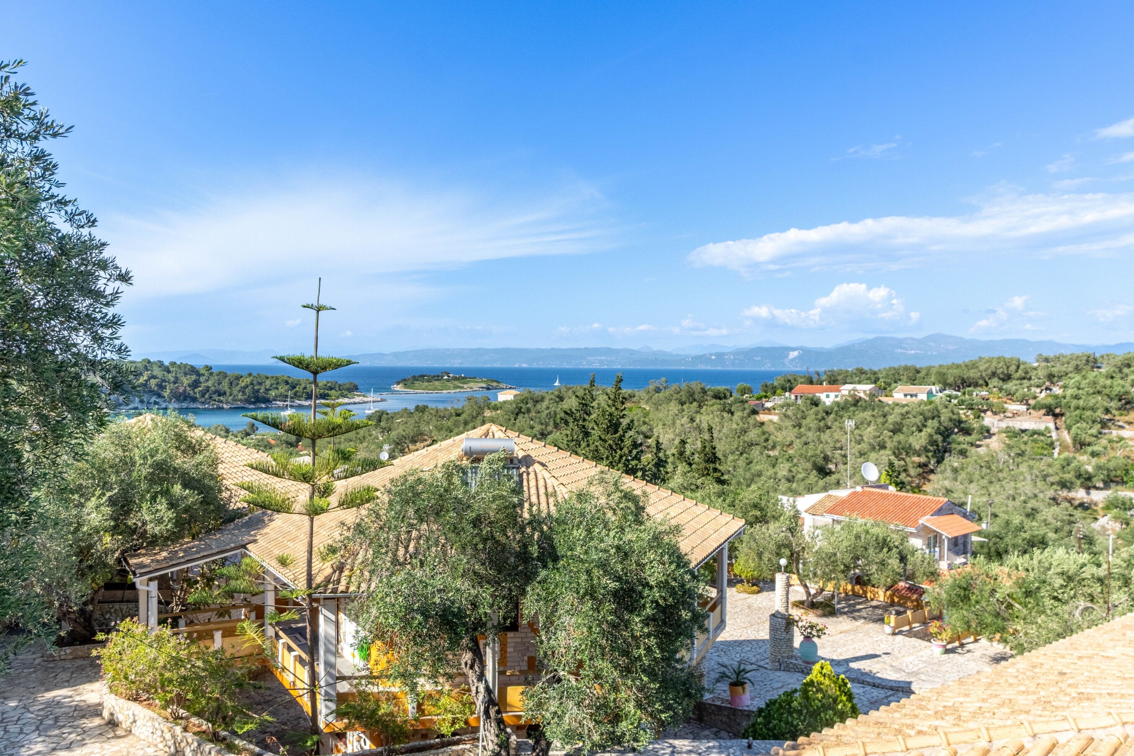A coastal property with terraced gardens, a view of the sea, and traditional architecture.