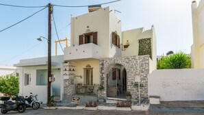 A two-story house with a stone archway entrance, a balcony, and a scooter parked outside. - Studio Apartment 'En Tino 3' with Balcony, Wi-Fi and Air Conditioning (Tinos)