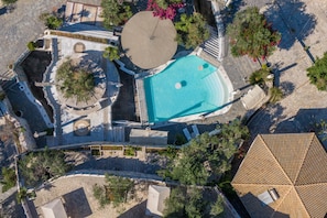 Luchtbeeld van een resort met een zwembad, een rond zitgedeelte en een overdekt terras.
