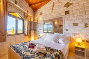 Een slaapkamer met een bed, een nachtkastje, een raam en uitzicht op het landschap.
