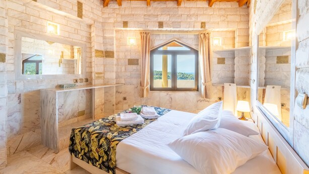 Una habitación con cama, ventana, espejo y techo de madera.