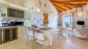 Una cocina moderna con encimeras de mármol, un comedor con sillas blancas y un televisor montado en la pared.