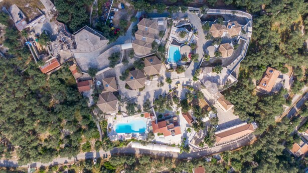 Eine Luftaufnahme eines Resorts mit Schwimmbad, mehreren Gebäuden und dichter Vegetation.
