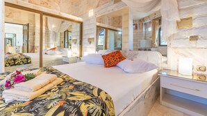 Ein Hotelzimmer mit einem großen Bett, einem Nachttisch, einem Spiegel und Blick ins Freie.