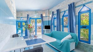 Habitació amb decoració en blaus i blancs, un sofà, una taula i un televisor.