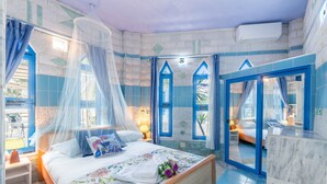 Ein Schlafzimmer mit einem Bett, einem Fenster, einem Nachttisch und einem Badezimmer mit einem Spiegel.