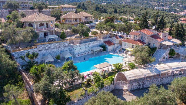 Ein Resort mit Schwimmbad, mehreren Gebäuden und einer hügeligen Landschaft.