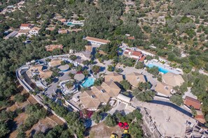 An aerial view of a residential area with houses, a swimming pool, and a large open space.