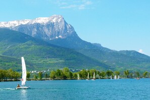 A lake with sailboats, a mountain in the background, and a shoreline with trees and buildings.