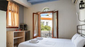 Een hotelkamer met een bed, een bureau, een stoel, een balkon en een raam met gordijnen.