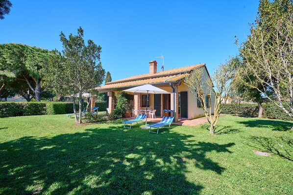A house with a patio, two lounge chairs, and a small table.