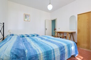 Une pièce comprenant un lit, un bureau, une chaise, une porte et un miroir.