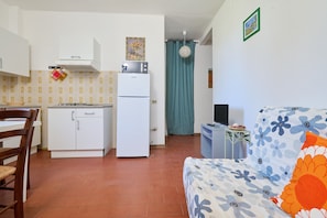 A compact living space with a kitchenette, a dining area, and a bed with floral bedding.