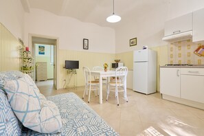 A compact living space with a dining area, kitchenette, and a bed with patterned bedding. - Apartment "Mare Etrusco 4" with Shared Garden & Wi-Fi (Populonia)