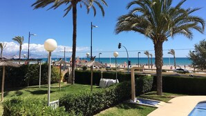 A beachside view with palm trees, a pool, and a clear blue sky. - Apartment '1a Linea San Juan Alicante' with Sea View, Wi-Fi and Air Conditioning (campello)