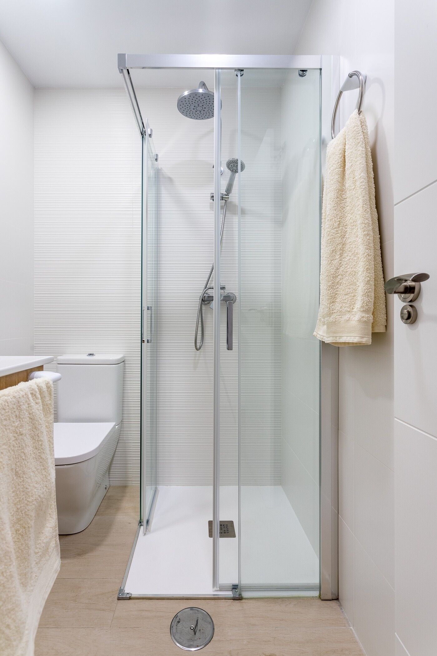 Un baño moderno con ducha de vidrio, inodoro y toallero.