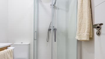 Un baño moderno con ducha de vidrio, inodoro y toallero.