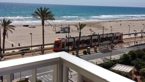 Blick auf einen Strand mit einer Straßenbahn, Palmen und blauem Himmel.