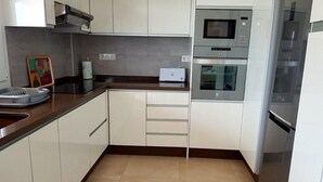 Eine Küche mit weißen Schränken, einer Mikrowelle, einem Backofen, einem Toaster und einem Spülbecken.