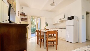 A compact kitchen with a refrigerator, stove, and dining area with chairs. - Apartment 'Mare Etrusco 3' with Shared Garden and Wi-Fi (Populonia)
