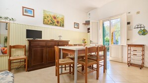 A dining area with a table and chairs, a television, and a cabinet. - Apartment 'Mare Etrusco 3' with Shared Garden and Wi-Fi (Populonia)