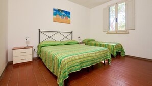 A bedroom with a bed, a nightstand, a window, and a painting on the wall. - Apartment 'Mare Etrusco 2' with Shared Garden and Wi-Fi (Populonia)