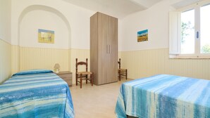 Ein Zimmer mit zwei Betten, einem Kleiderschrank, einem Stuhl und einem Fenster.