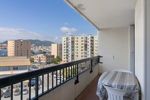 A balcony with a view of a cityscape, including high-rise buildings and a body of water.