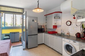 Eine kleine Küche mit Kühlschrank, Mikrowelle, Spüle und Waschmaschine.