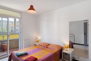 Une chambre à coucher avec un lit, deux lampes de chevet, une fenêtre et un miroir.