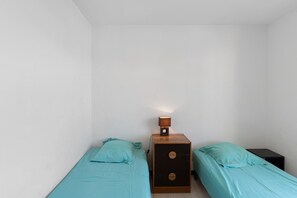 Ein kleines Zimmer mit zwei Betten, einem Nachttisch mit Lampe und einer Kommode.
