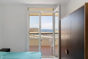 Ein Zimmer mit einem Bett, einer Schiebetür zum Balkon und Meerblick.