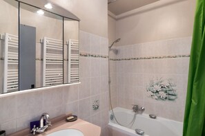 Ein Badezimmer mit Waschbecken, Spiegel, Handtuchhalter, Dusche und einem grünen Vorhang.