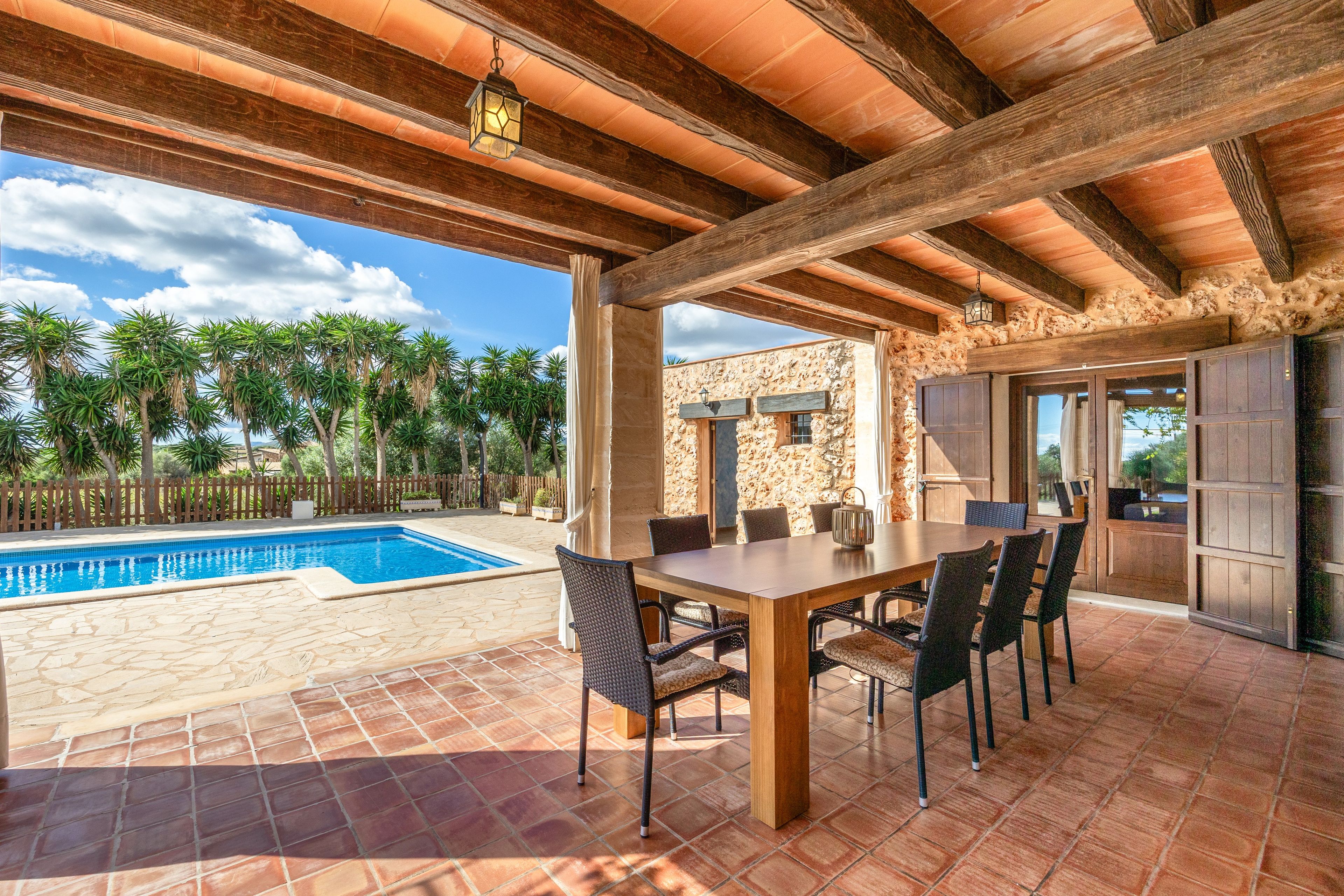 An outdoor patio with a pool, dining table, and chairs.