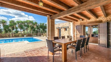 An outdoor patio with a pool, dining table, and chairs.