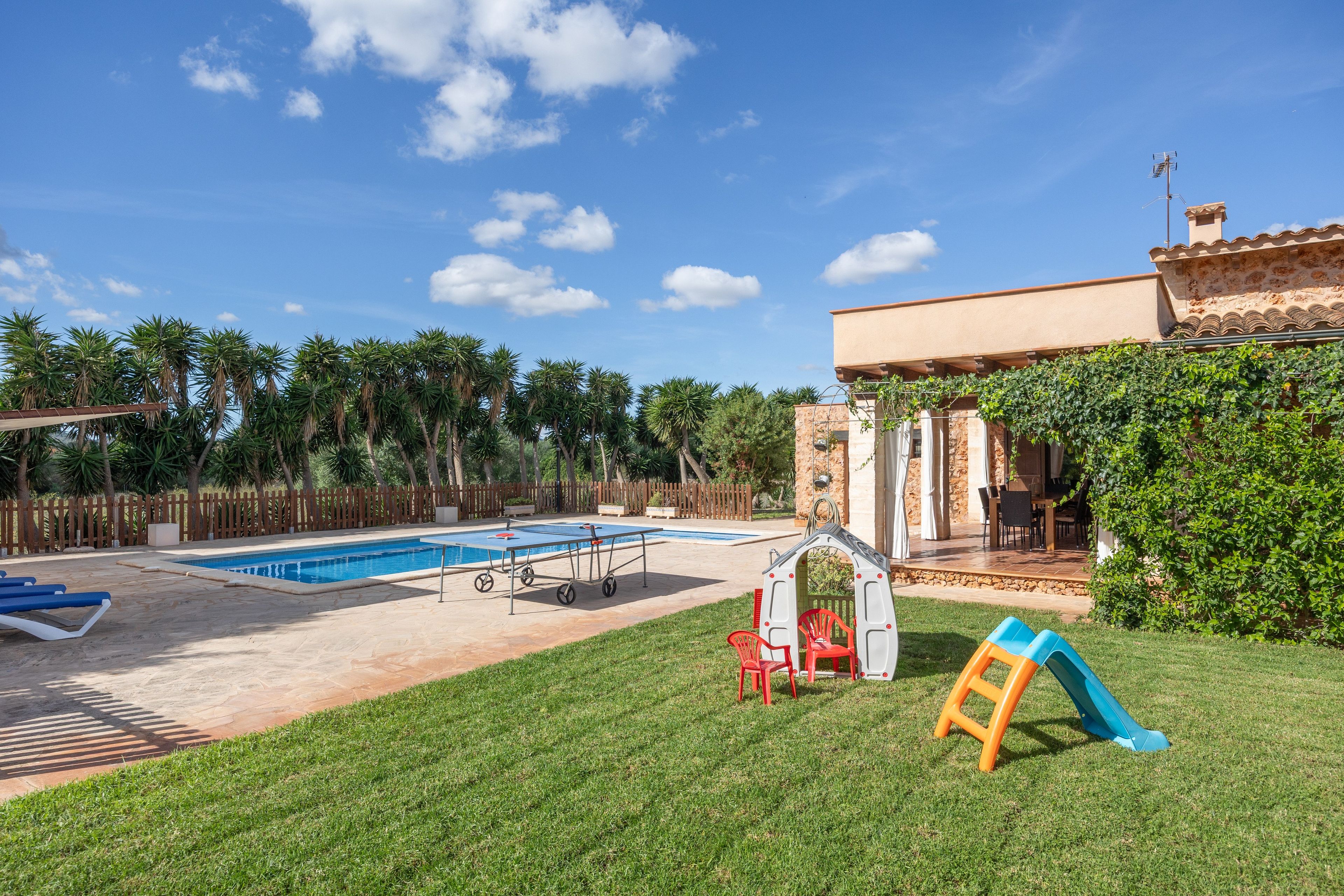 A backyard with a swimming pool, a playhouse, and a slide.