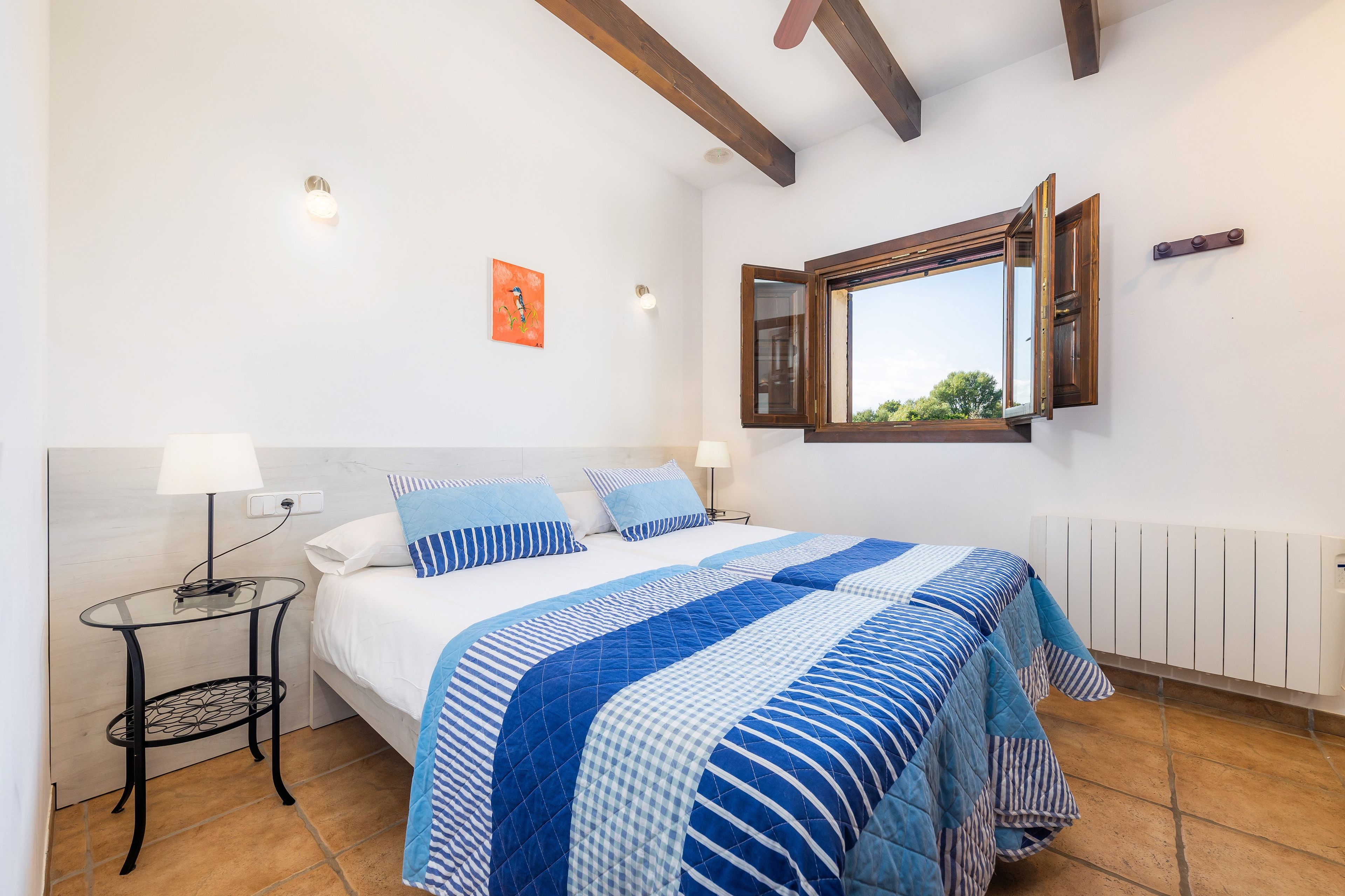 A bedroom with a bed, bedside tables, a window, and a radiator.