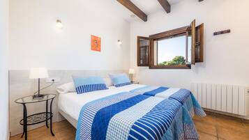 A bedroom with a bed, bedside tables, a window, and a radiator.