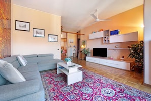 A living room with a grey sofa, a white coffee table, a flat-screen TV, and a patterned rug. - Holiday Home "House of Roses" with Private Terrace & Wi-Fi (Como)