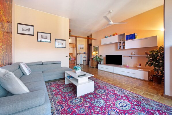 A living room with a grey sofa, a white coffee table, a flat-screen TV, and a patterned rug. - Holiday Home "House of Roses" with Private Terrace and Wi-Fi (Como)