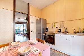 A kitchen with a dining table set for four, a refrigerator, oven, and a sink. - Holiday Home "House of Roses" with Private Terrace & Wi-Fi (Como)
