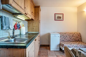 A compact kitchen with wooden cabinets, a sink, and a dishwasher.