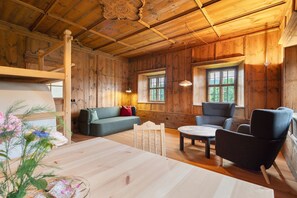 A wooden interior with a sofa, chairs, a table, and a window. - Apartment 'Ansitz Baumannhof 1818' with Mountain View, Shared Garden and Wi-Fi (Pfalzen)