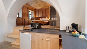 Een keuken met houten kastjes, een ingebouwde oven, een magnetron en een koffiezetapparaat.